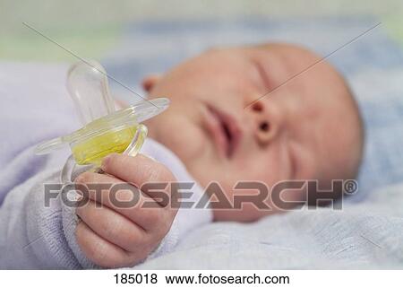 Stock Photo - Newborn baby sleeping and holding pacifier. Fotosearch