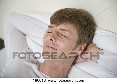 Man lying down on bed with eyes closed and hands behind head View Large Photo Image Stock Image - Man lying down on bed with eyes closed and hands behind head. Fotosearch