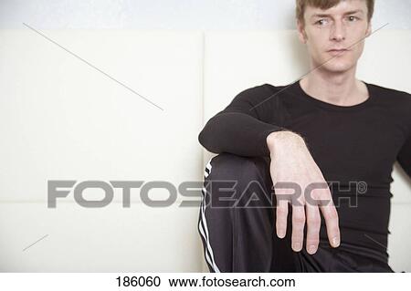 Stock Image - Man sitting on sofa and looking away. Fotosearch