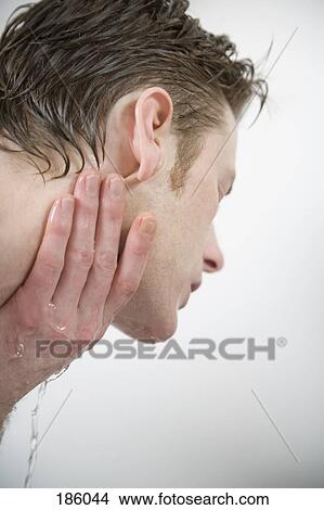 Picture - Man splashing water on his face and neck. Fotosearch