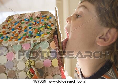 Young boy licking gingerbread house View Large Photo Image Stock Photo - Young boy licking gingerbread house. Fotosearch