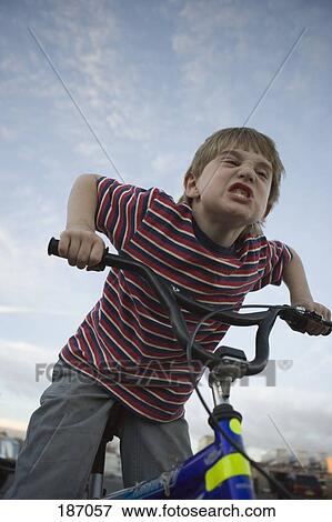 Stock Photo - Young boy making face on bicycle. Fotosearch