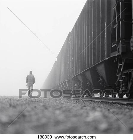 Man walking next to freight train View Large Photo Image Stock Photo - Man walking next to freight train. Fotosearch