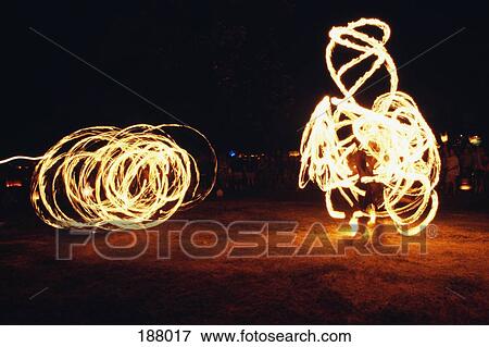 Stock Photo - Two fire-twirlers at night. Fotosearch