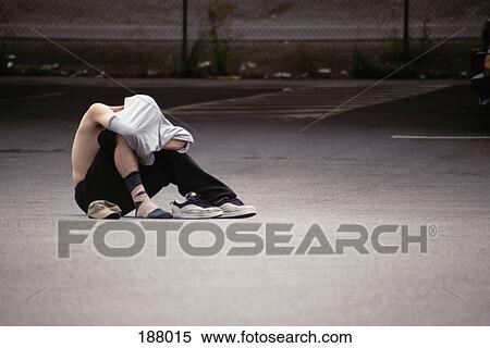 Young man sitting down and covering his head View Large Photo Image Stock Photography - Young man sitting down and covering his head. Fotosearch
