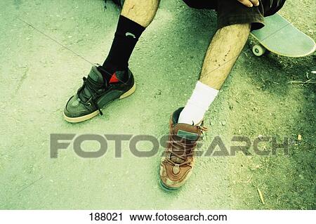 Young man sitting on skateboard wearing different shoes and socks View Large Photo Image Stock Image - Young man sitting on skateboard wearing different shoes and socks. Fotosearch
