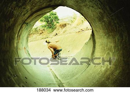 Picture - Young man skateboarding through tunnel. Fotosearch