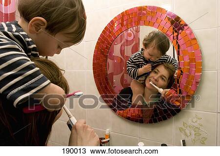 Stock Image - Mother and son brushing teeth together. Fotosearch