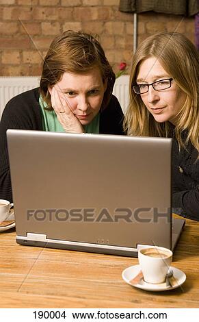 Two women sitting in cafe using laptop View Large Photo Image Picture - Two women sitting in cafe using laptop. Fotosearch