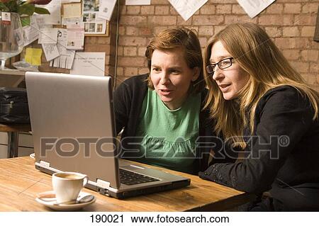 Two women sitting in cafe using laptop View Large Photo Image Stock Image - Two women sitting in cafe using laptop. Fotosearch