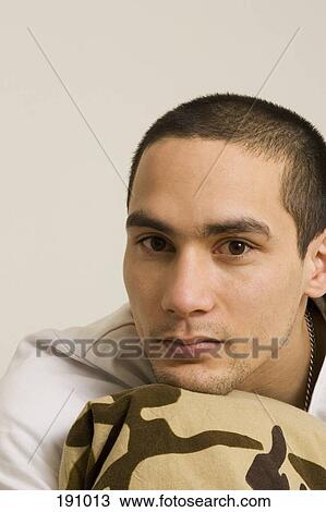 Stock Image - Man sitting with chin on knee. Fotosearch