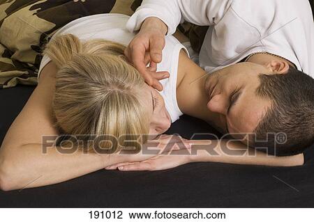 Young couple lying down on bed View Large Photo Image Stock Image - Young couple lying down on bed. Fotosearch