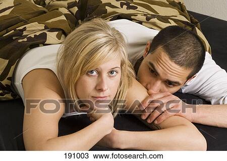 Young couple lying on bed View Large Photo Image Stock Image - Young couple lying on bed. Fotosearch