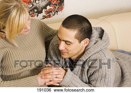 Young couple on sofa interlocking hands View Large Photo Image Stock Photograph - Young couple on sofa interlocking hands. Fotosearch