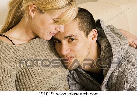 Young couple sitting together on sofa View Large Photo Image Stock Photo - Young couple sitting together on sofa. Fotosearch