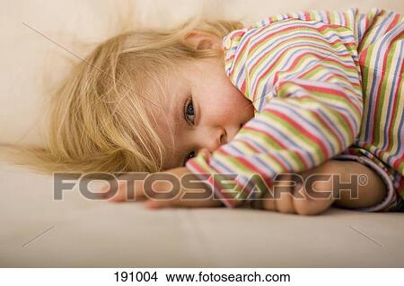 Picture - Young girl lying down on sofa. Fotosearch
