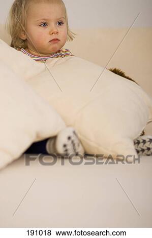 Young girl sitting on sofa buried in cushions View Large Photo Image Stock Photo - Young girl sitting on sofa buried in cushions. Fotosearch