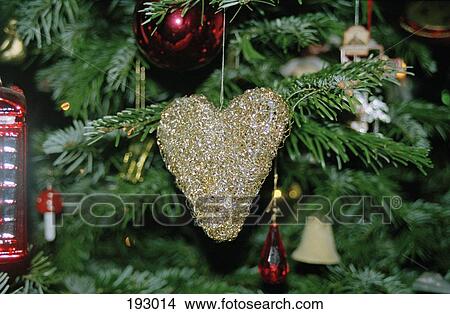 Gold heart hanging on Christmas tree View Large Photo Image Picture - Gold heart hanging on Christmas tree. Fotosearch