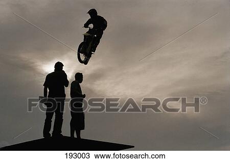 Stock Image - Person riding motorcycle in mid-air. Fotosearch