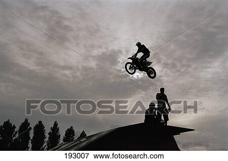 Person riding motorcycle over jump in mid-air View Large Photo Image Stock Photo - Person riding motorcycle over jump in mid-air. Fotosearch