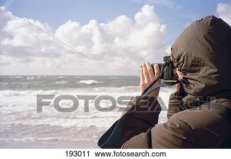 Stock Image - Person taking photograph on beach. Fotosearch