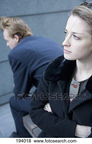 Businesswoman standing with arms crossed and businessman sitting behind with back turned View Large Photo Image Stock Photo - Businesswoman standing with arms crossed and businessman sitting behind with back turned. Fotosearch