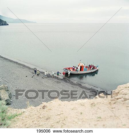 Stock Photograph - A group of people boarding a brightly painted boat. Fotosearch