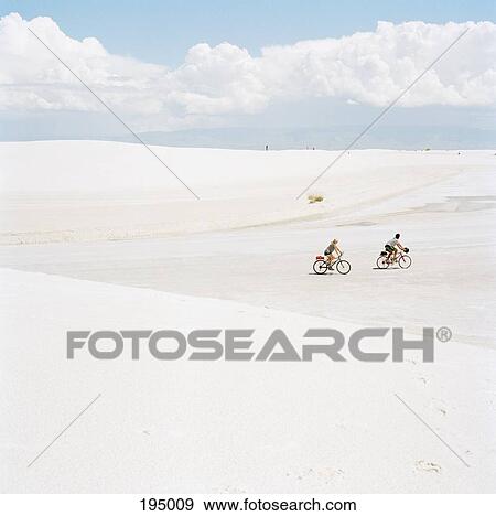 Two people cycling in a barren landscape View Large Photo Image Stock Photo - Two people cycling in a barren landscape. Fotosearch