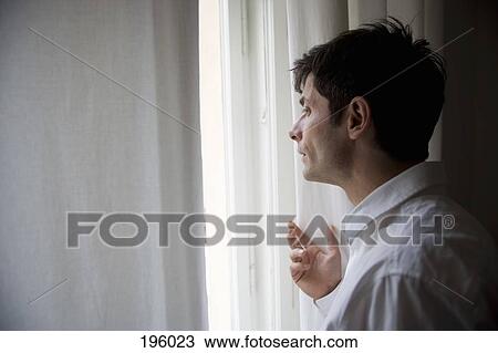 Stock Image - A man looking out a window. Fotosearch