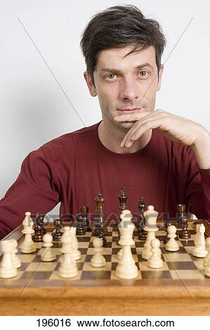 A man sitting in front of a chess set View Large Photo Image Stock Photograph - A man sitting in front of a chess set. Fotosearch