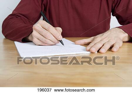 Stock Photo - A man writing on a pad of paper. Fotosearch
