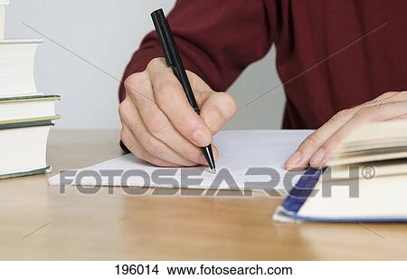 Picture - A person writing on a pad of paper. Fotosearch