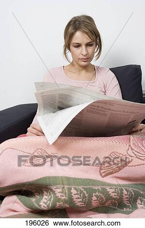 a woman sitting on a couch reading a newspaper View Large Photo Image Stock Photograph - a woman sitting on a couch reading a newspaper. Fotosearch