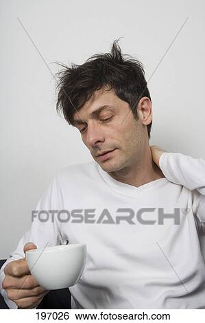 Stock Photograph - A disheveled man holding a cup of tea. Fotosearch