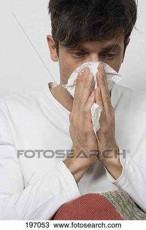 Stock Image - A man blowing his nose. Fotosearch