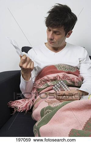 Stock Photo - A man holding a package of pills and instructions. Fotosearch
