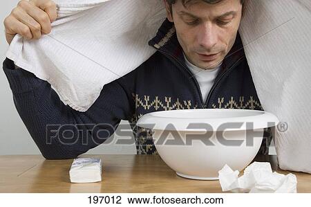 Stock Image - A man with a cold breathing steam from a bowl. Fotosearch