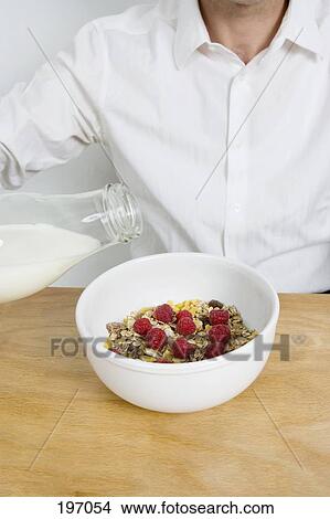 Man pouring milk into a bowl of cereal View Large Photo Image Picture - Man pouring milk into a bowl of cereal. Fotosearch
