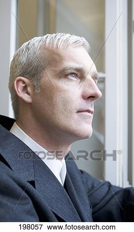 A businessman looking out of a window View Large Photo Image Stock Photo - A businessman looking out of a window. Fotosearch