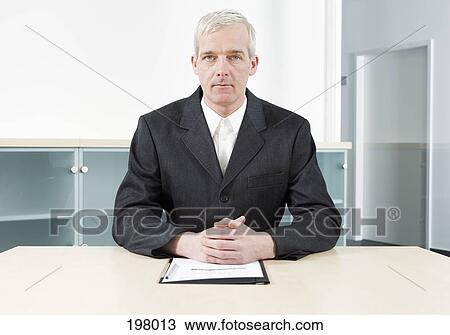 A businessman sitting at a conference table View Large Photo Image Stock Image - A businessman sitting at a conference table. Fotosearch