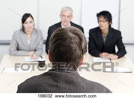 Stock Image - A man being interviewed by three people. Fotosearch