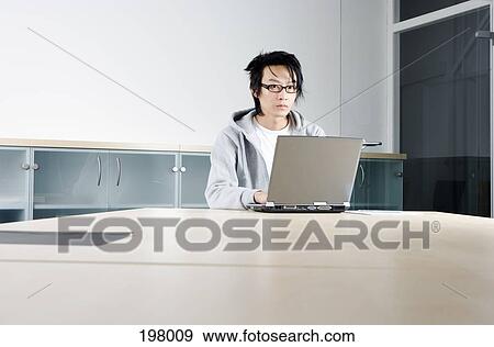 A man working on a laptop at a conference table View Large Photo Image Stock Photo - A man working on a laptop at a conference table. Fotosearch