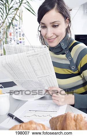 A woman reading a newspaper while having breakfast View Large Photo Image Stock Photo - A woman reading a newspaper while having breakfast. Fotosearch