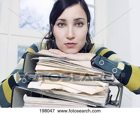 Stock Photo - A woman resting her head on a stack of binders. Fotosearch
