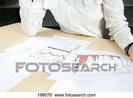 A woman reviewing paperwork featuring graphs and charts View Large Photo Image Stock Image - A woman reviewing paperwork featuring graphs and charts. Fotosearch