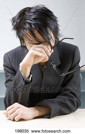 Stock Photography - An Asian businessman experiencing stress and exhaustion. Fotosearch