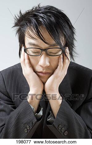 An Asian businessman resting his head in his hands View Large Photo Image Stock Photo - An Asian businessman resting his head in his hands. Fotosearch