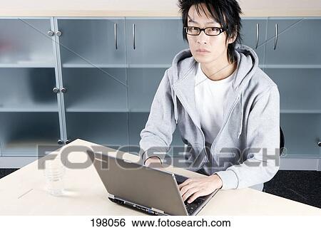 An Asian man working on a laptop View Large Photo Image Stock Photograph - An Asian man working on a laptop. Fotosearch