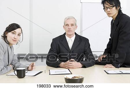 Stock Image - Three businesspeople in a conference room. Fotosearch