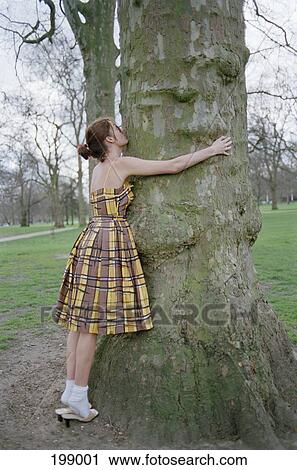 Stock Image - A woman hugging a tree. Fotosearch